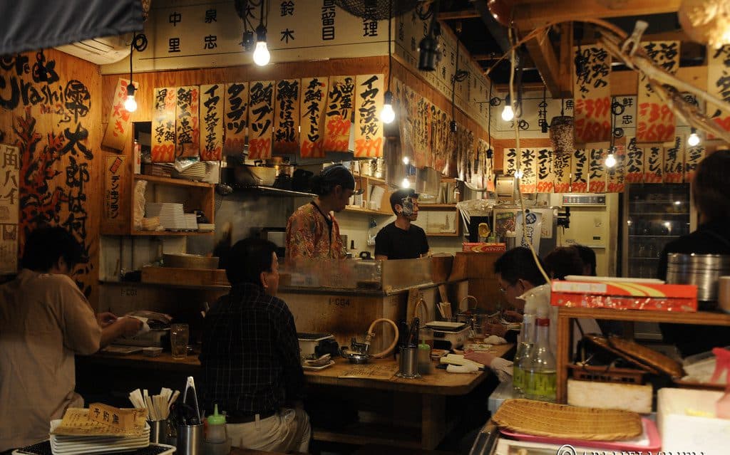 Warm izakaya counter lined with handwritten menu boards